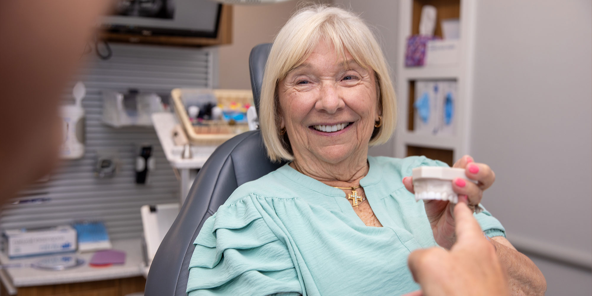 Paitent Smiling at doctor holding a model of dental implants